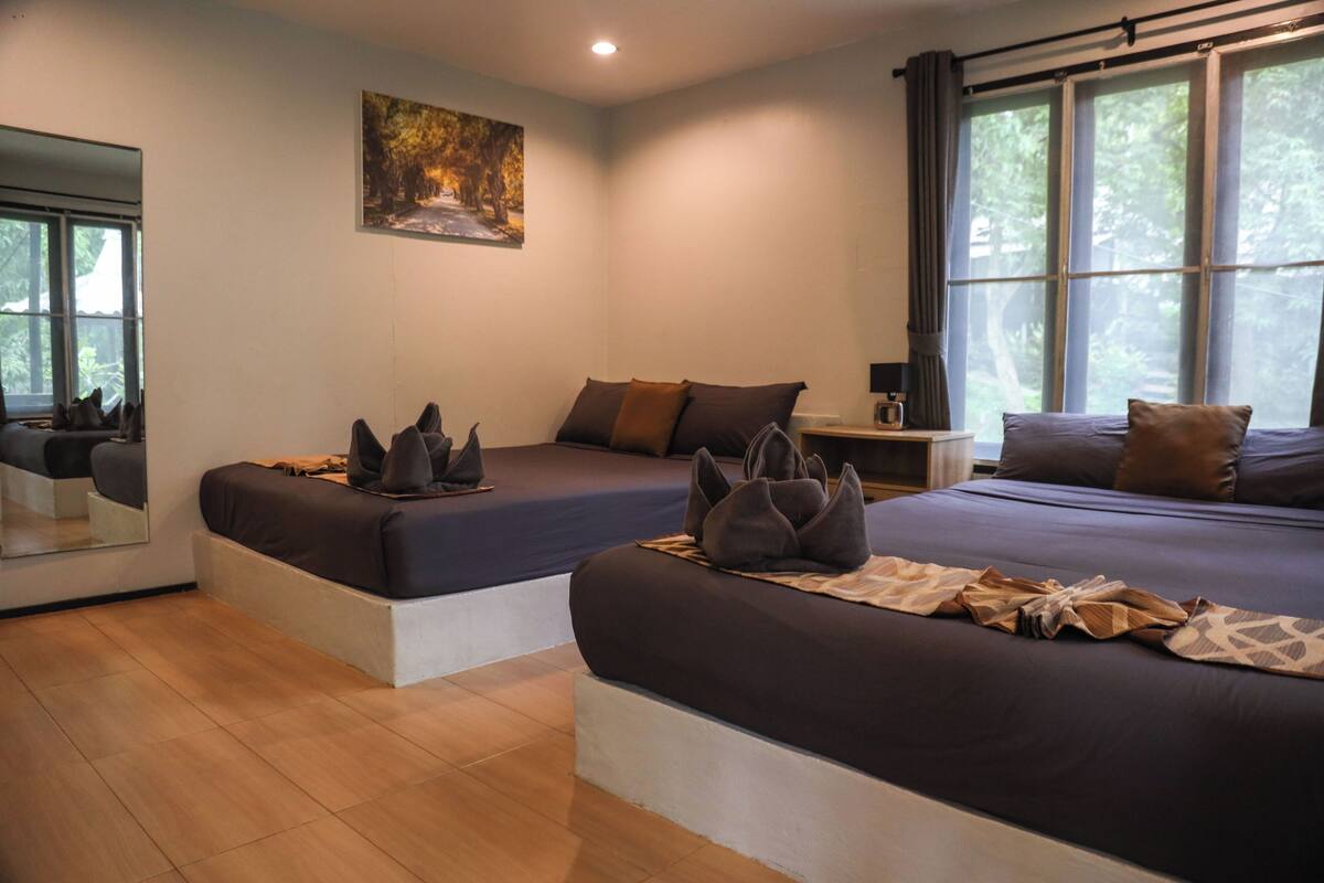Quarto de hotel moderno com duas camas, uma janela grande com cortinas, um quadro na parede e um espelho refletindo o quarto.