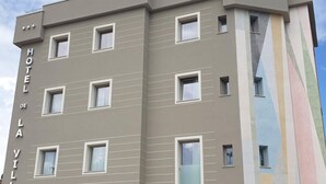 A multi-story hotel building with a modern facade, featuring a series of windows and a distinctive vertical design element on the right side.