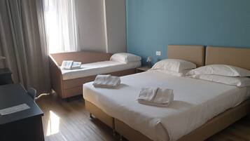 A hotel room with two beds, a desk, and a window with curtains.
