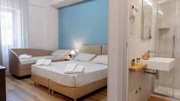 Une chambre d’hôtel comprenant un lit, des tables de chevet, un bureau, un espace douche et une salle de bain avec un lavabo.