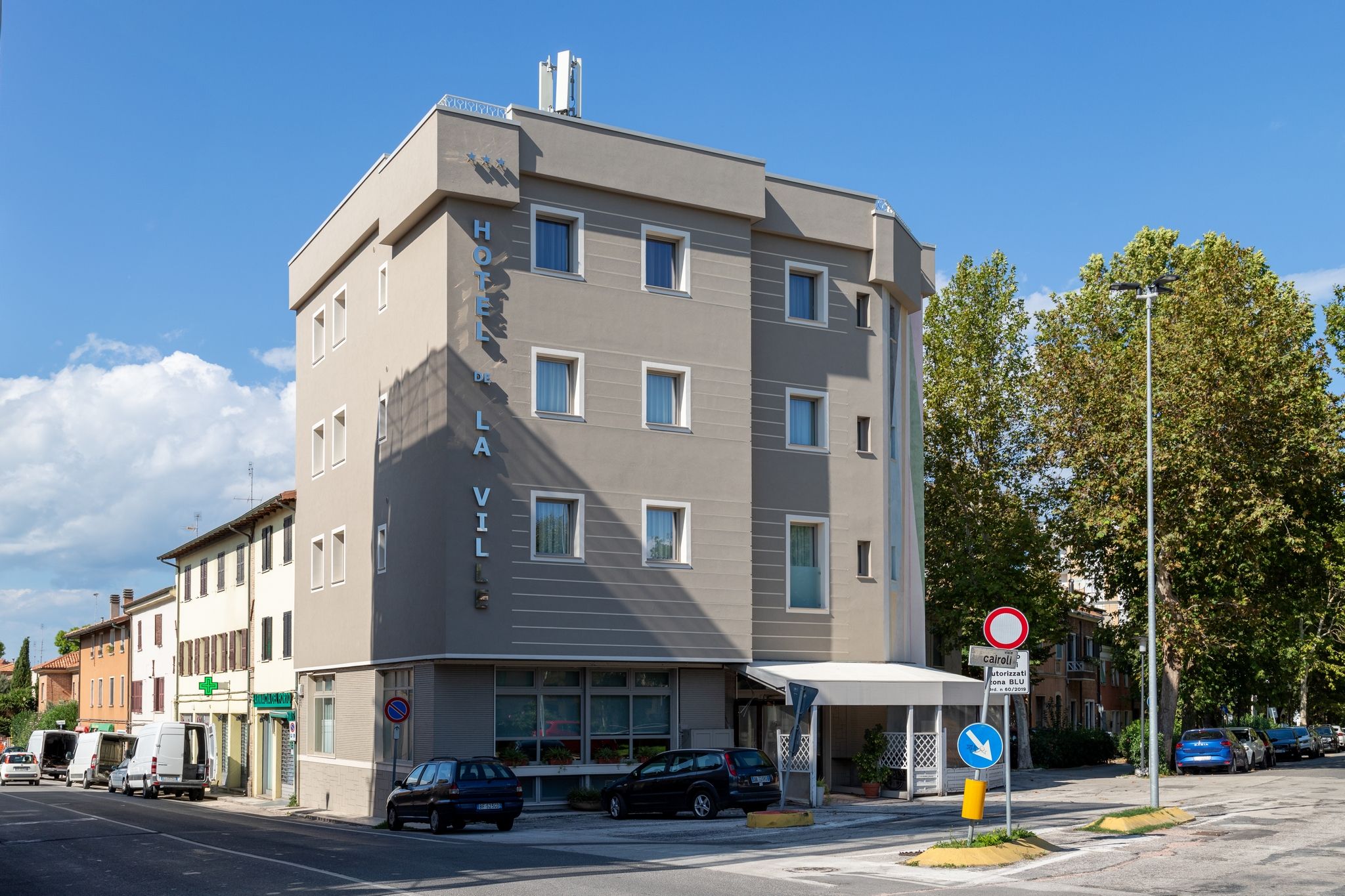 Un hotel de varios pisos con fachada plana, múltiples ventanas y una entrada visible.