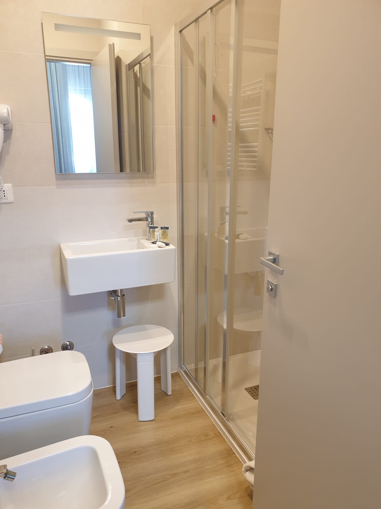 Ein modernes Badezimmer mit einer Duschkabine aus Glas, einem weißen Waschbecken und einem Bidet.