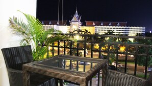 Un balcón con mobiliario de mimbre y vistas a un edificio de estilo arquitectónico tradicional.