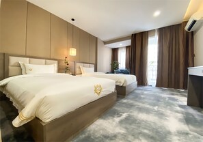 Habitación de hotel con dos camas, un ventanal con cortinas, una planta y un escritorio.