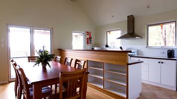A spacious kitchen with a wooden dining table, white cabinets, and a large window.
