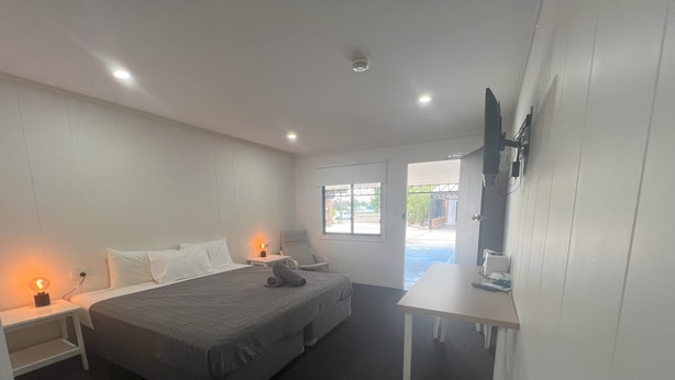 Ein Hotelzimmer mit Bett, Nachttischen, einem Schreibtisch und einem Fernseher.
