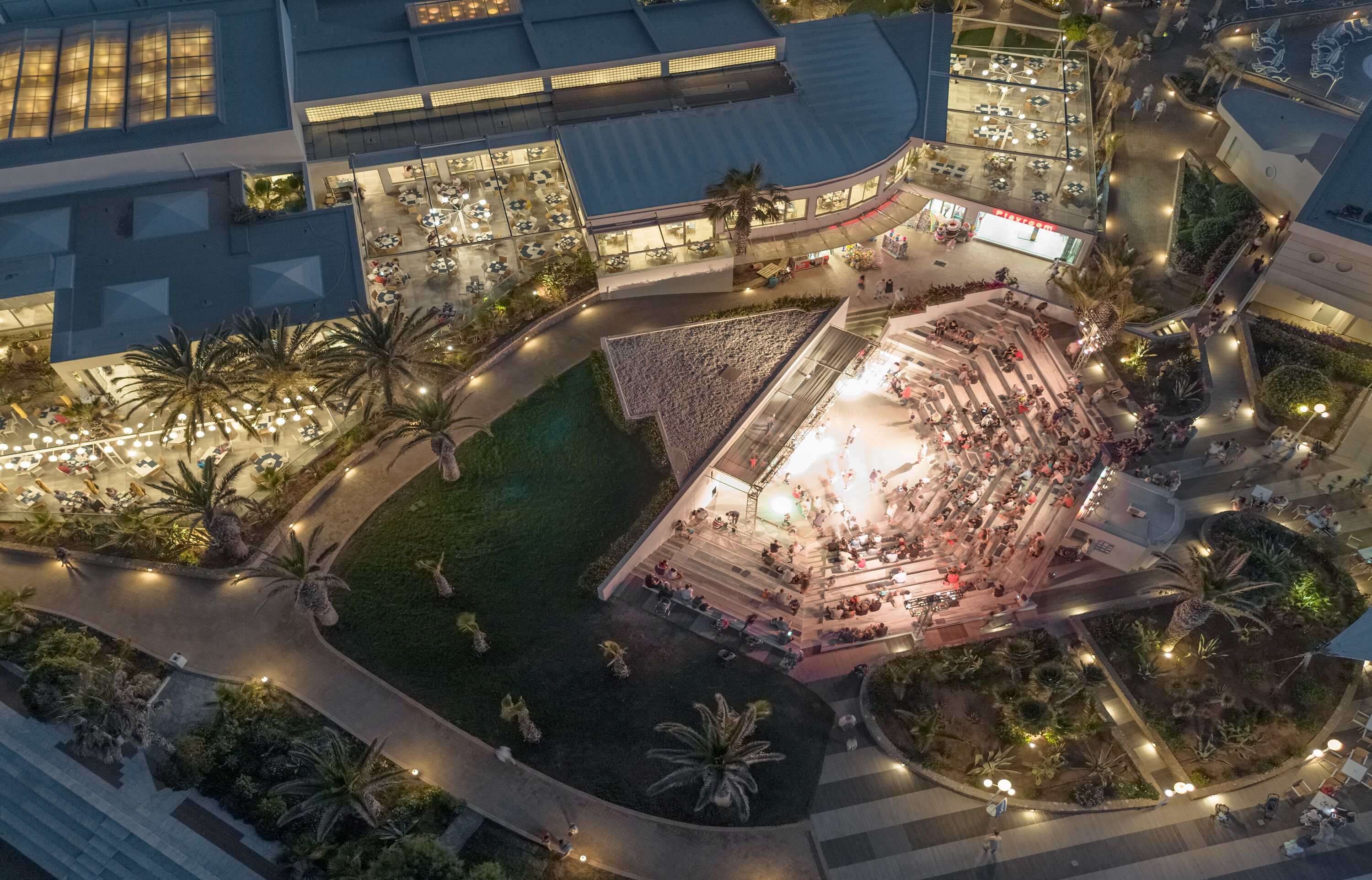 An aerial view of a hotel with a central courtyard, outdoor seating area, and surrounding greenery.