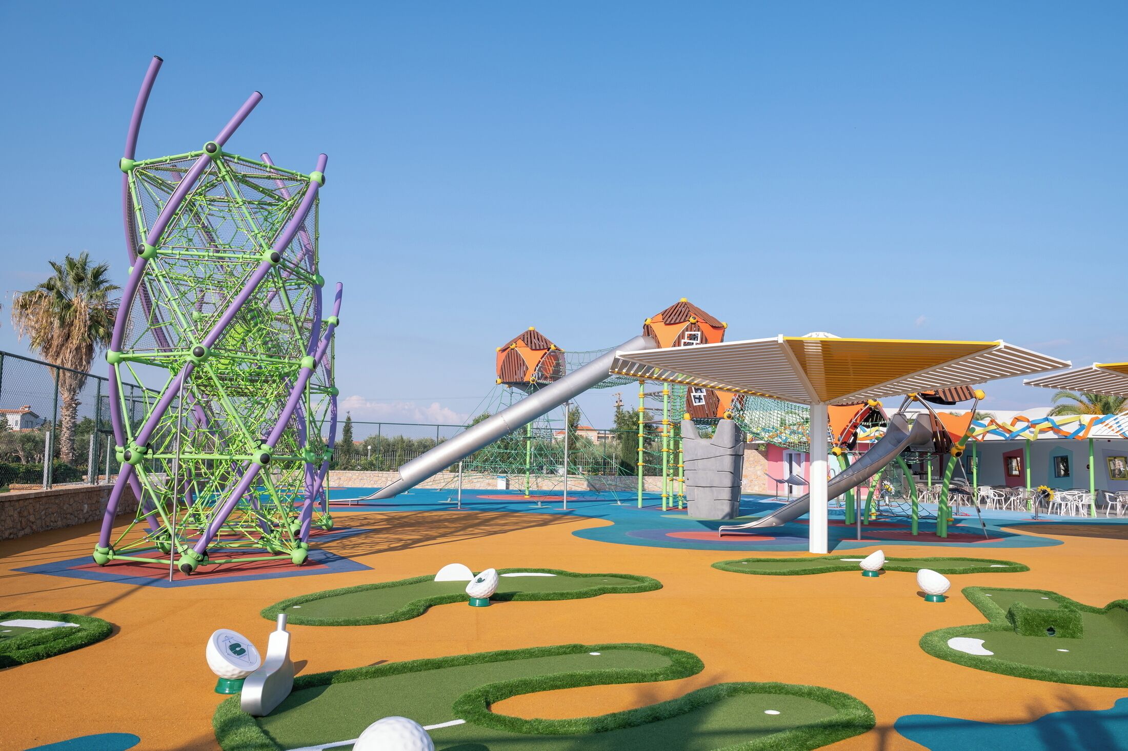 A playground with climbing structures, slides, and artificial turf.