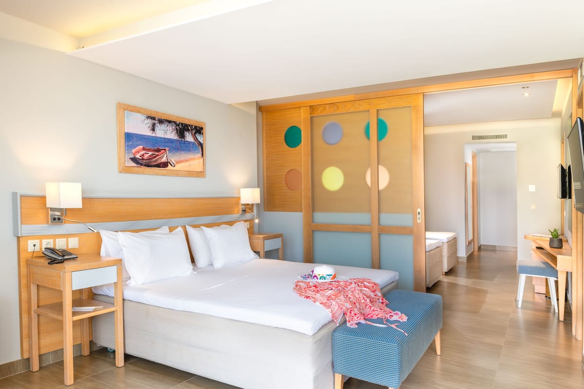 A hotel room with a bed, bedside tables, a desk, and a TV.