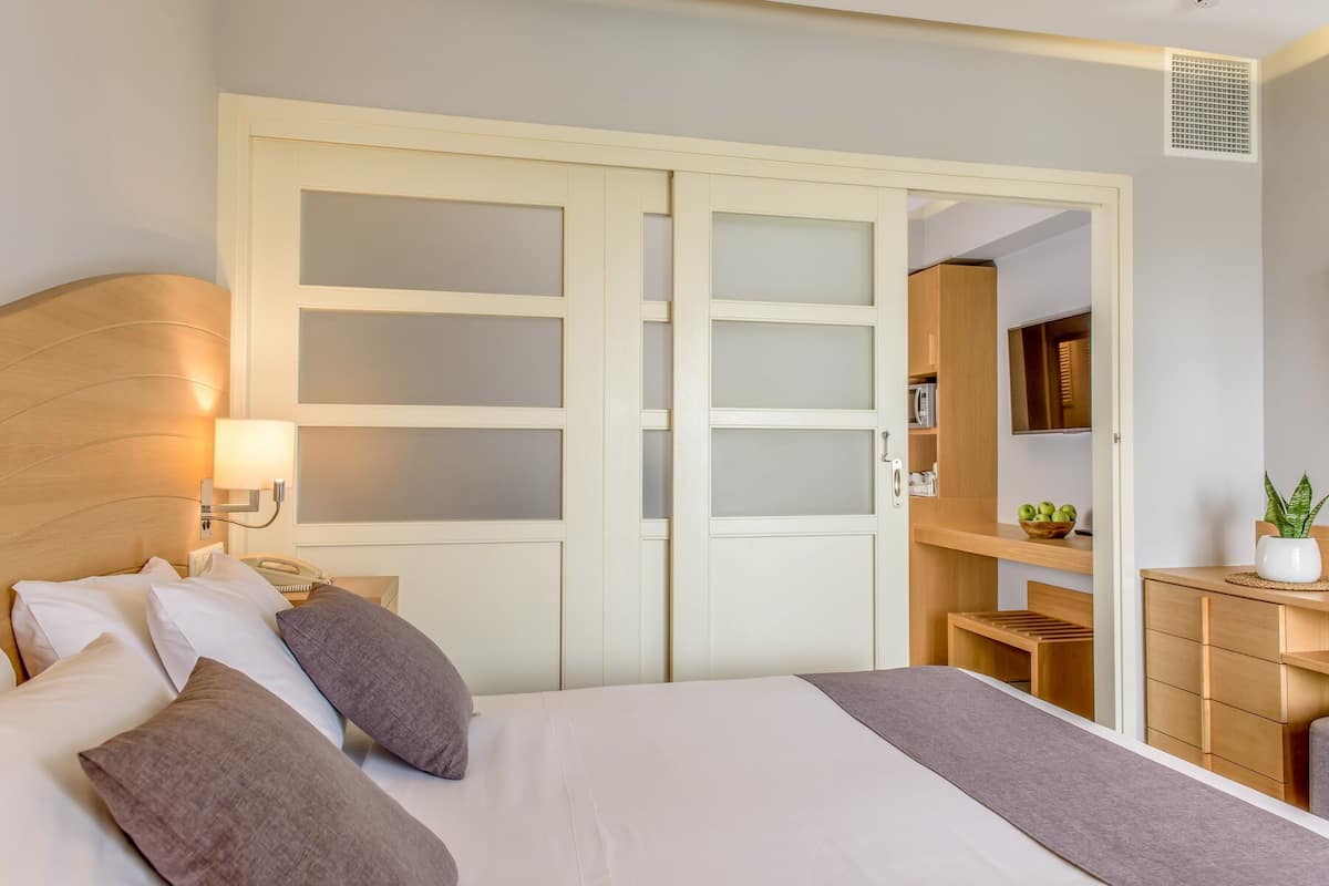 A hotel room with a bed, bedside lamp, and a wardrobe with frosted glass doors.