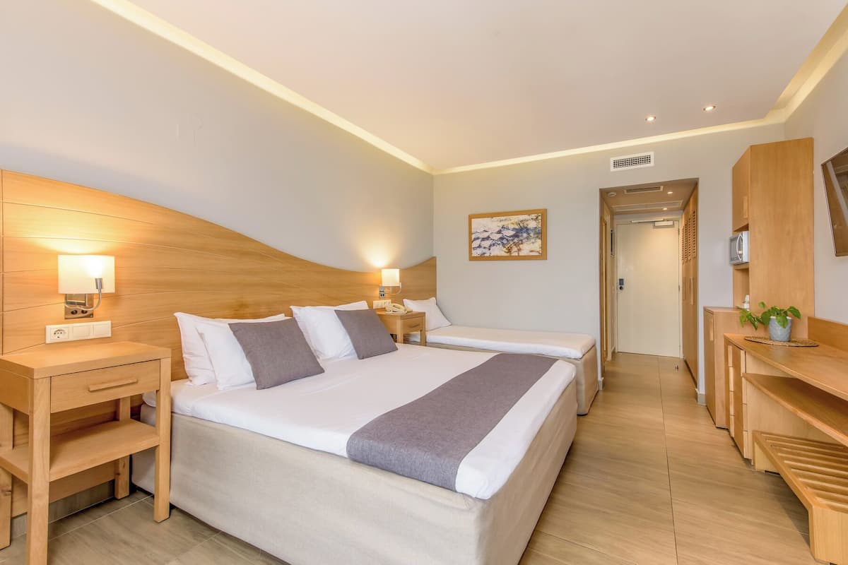 A hotel room with two beds, bedside tables, a desk, and a chair.