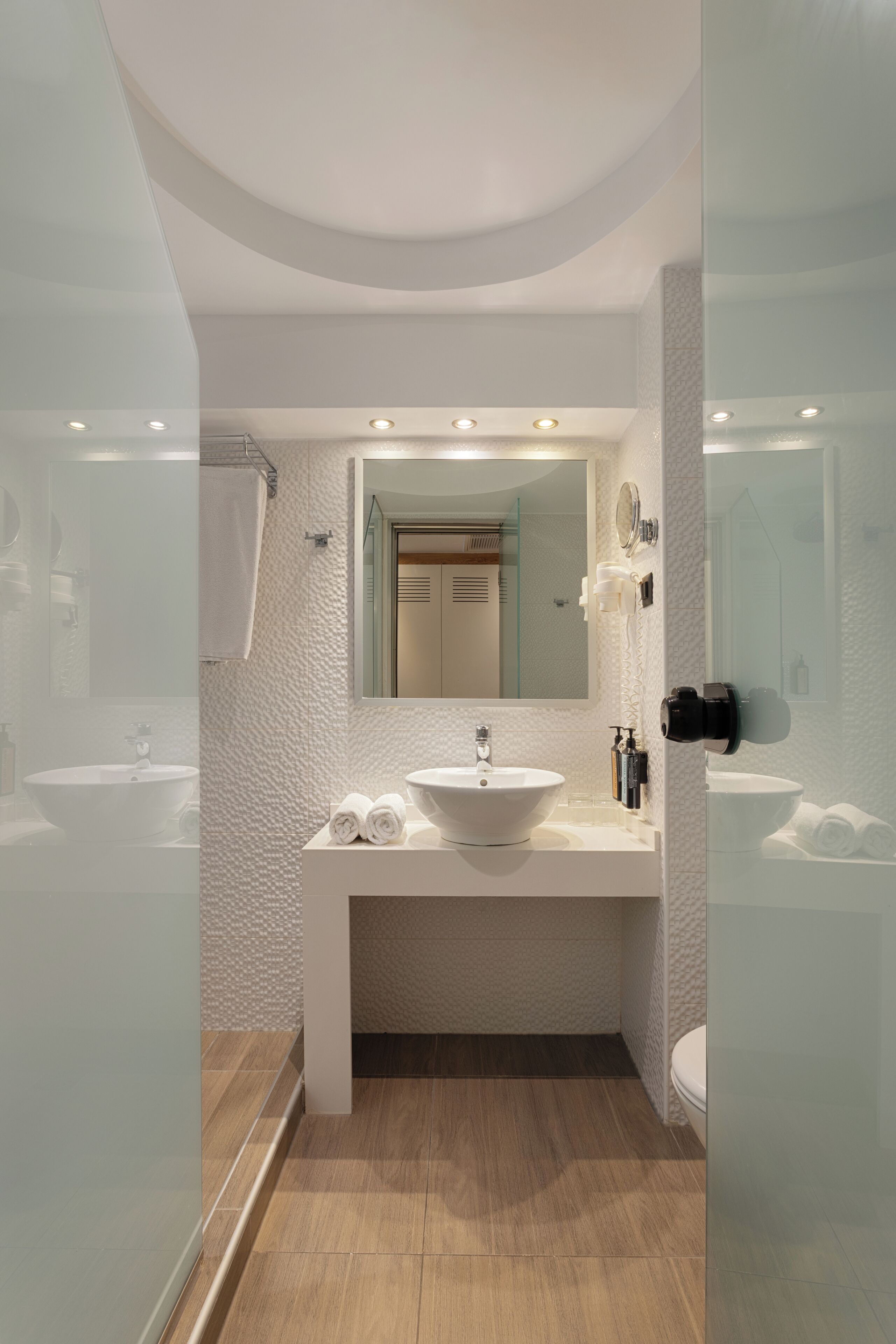 Un baño moderno con un espejo grande, dos lavamanos, un inodoro y una zona de ducha.