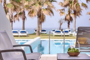 Zona junto a la piscina con sillas de descanso y vista al océano.