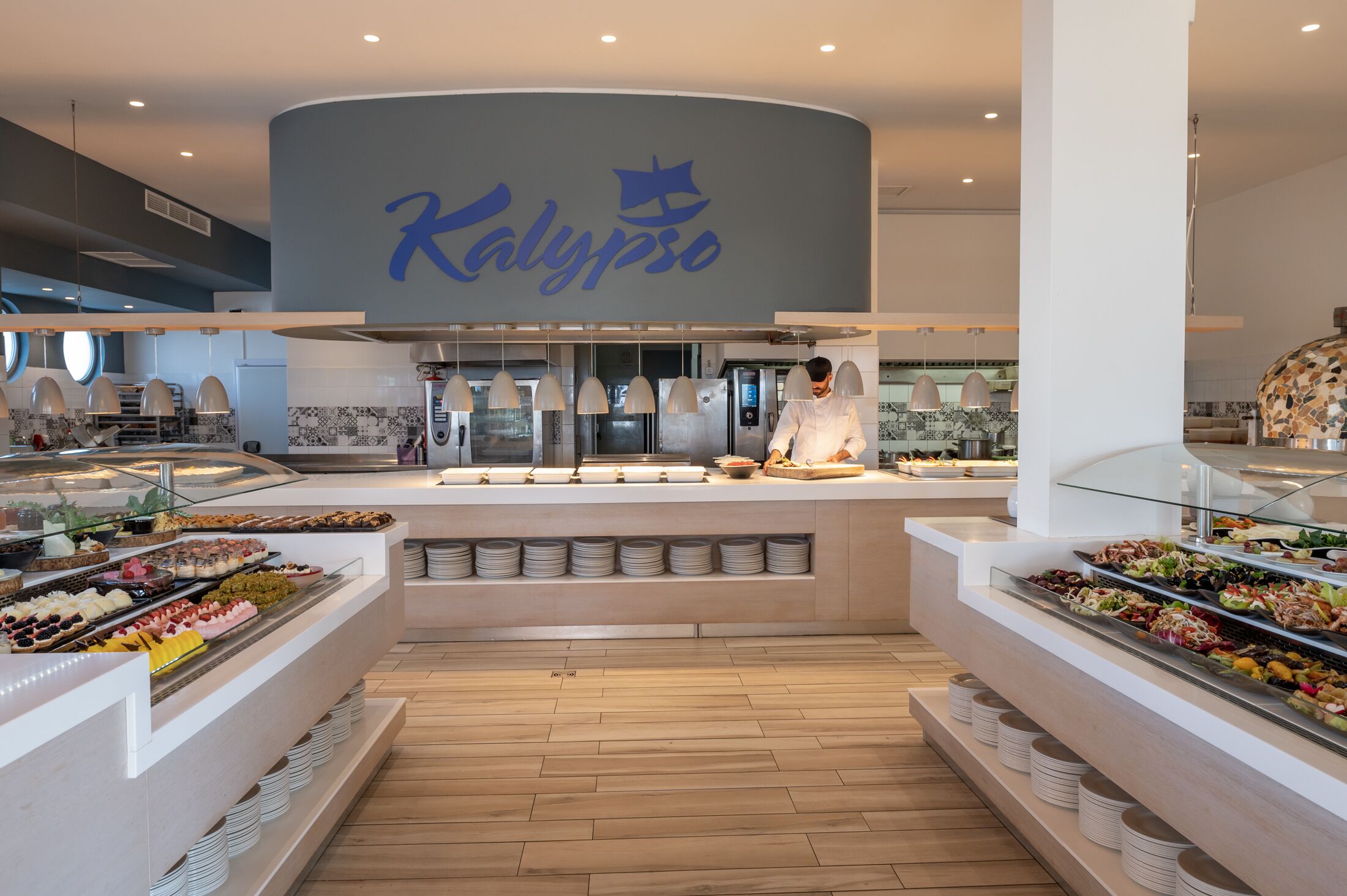 Een buffetgedeelte met een kok die eten bereidt, een groot bord met de tekst 