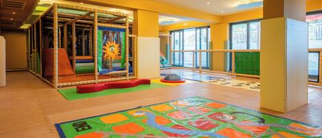 A children's play area with a soft play structure, a colorful mat, and a large window.