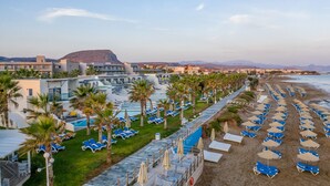 Ein Resort mit Poolbereich, Strand und Bergblick.