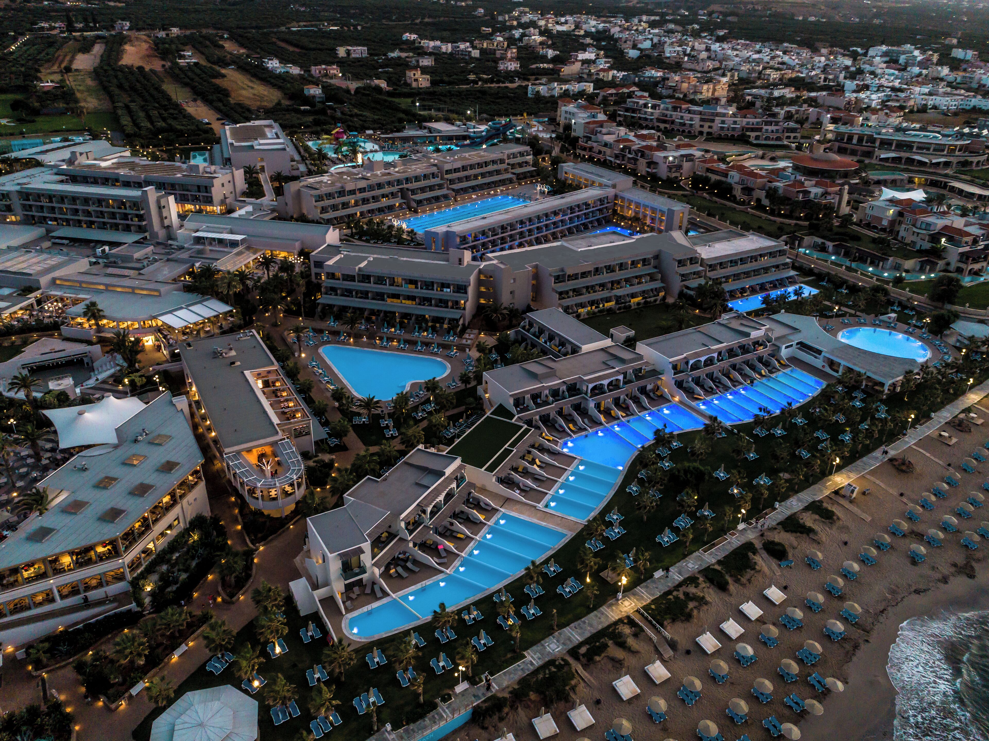 A resort with multiple swimming pools, a beach area, and a variety of buildings.