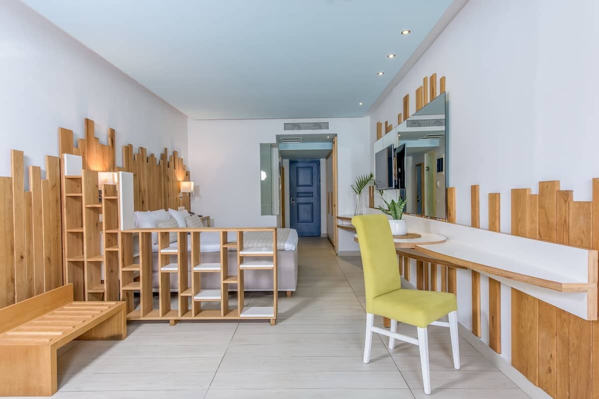 A modern hotel room with a wooden accent wall, a bed, a desk, and a chair.