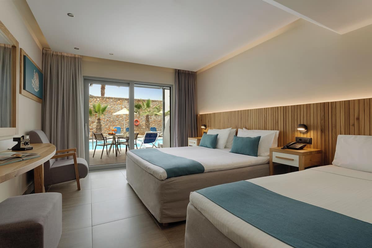 A hotel room with two beds, a desk, and a view of an outdoor pool area.