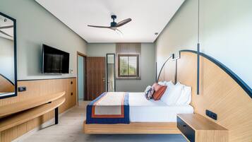 Ein modernes Schlafzimmer mit Bett, Nachttisch, integriertem Fernseher, Deckenventilator und einem Fenster mit Jalousien.