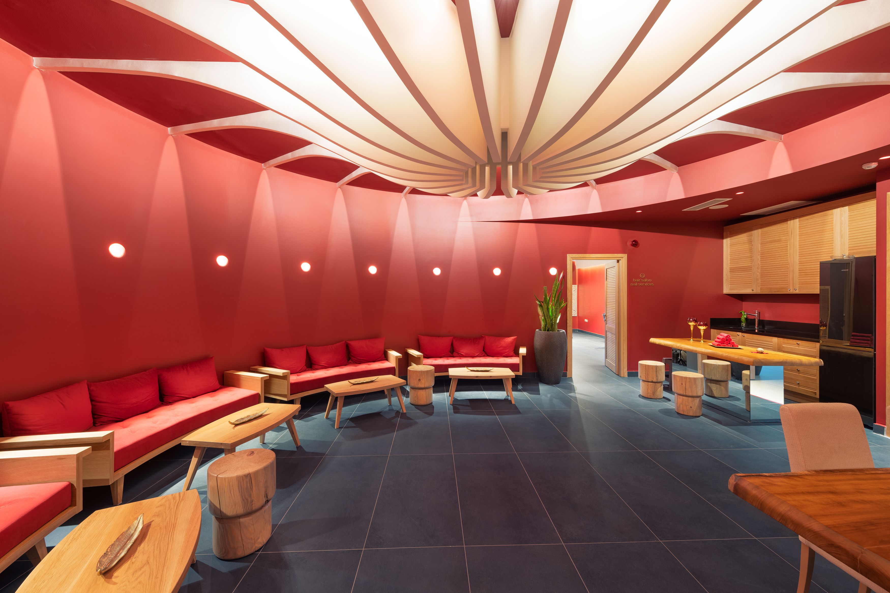 A modern interior with red walls, wooden furniture, and a unique ceiling design.