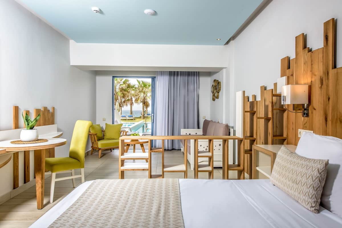 A hotel room with a bed, a desk, a chair, and a view of the ocean.