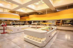Una moderna disposición de bufé con varias estaciones de servicio, una isla central con platos y un interior limpio y luminoso.