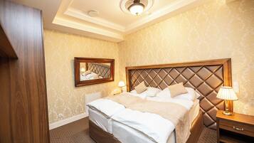 A hotel room with a large bed, a nightstand, a mirror, and a ceiling light.
