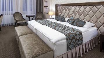 A hotel room with a large bed, a desk, two chairs, and a small table.
