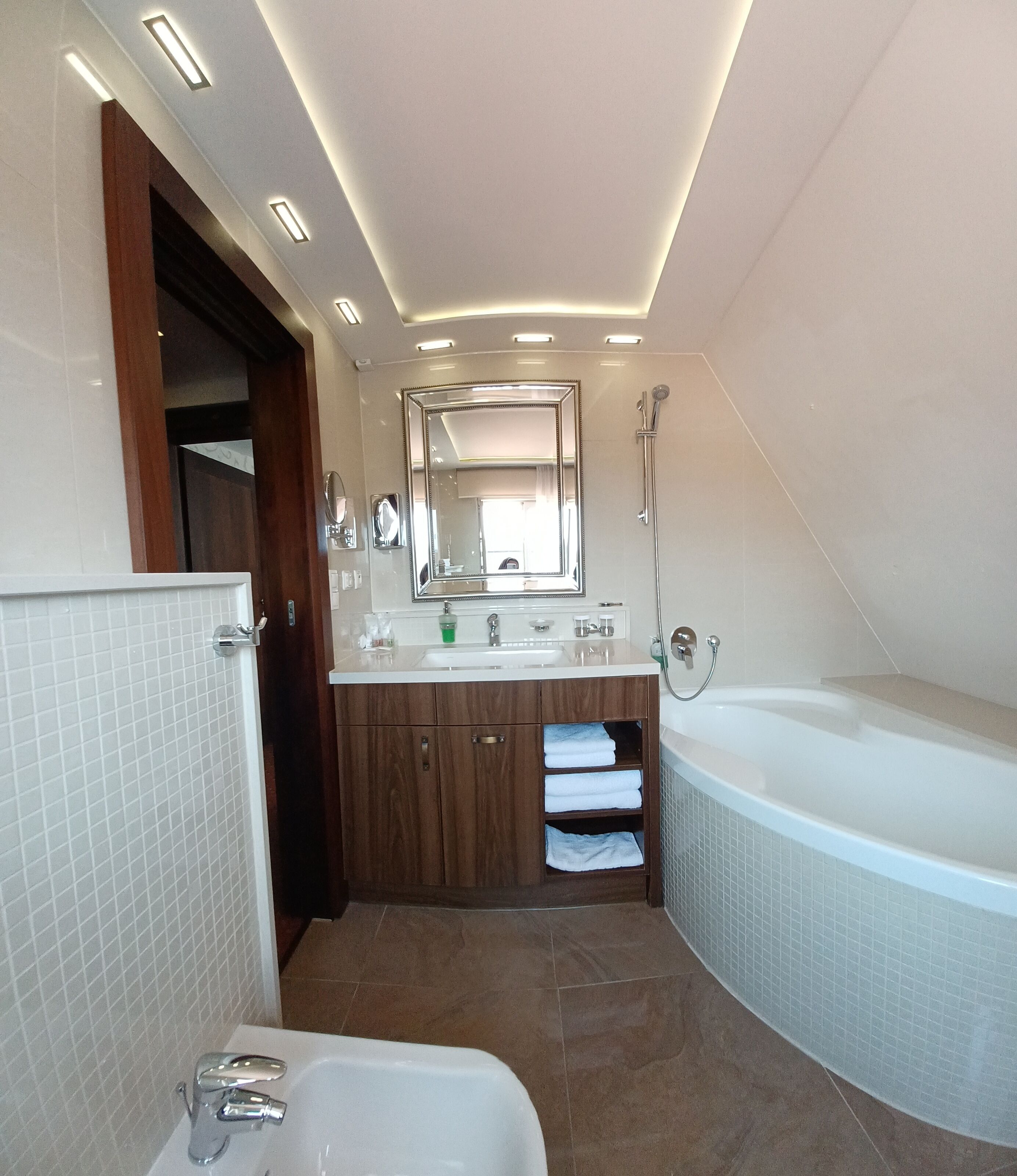 A modern bathroom with a bathtub, a sink, a vanity with a mirror, and a shower.