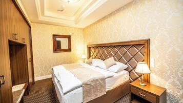 Een hotelkamer met een groot bed, een houten garderobe, een nachtkastje met een lamp en een spiegel aan de muur.