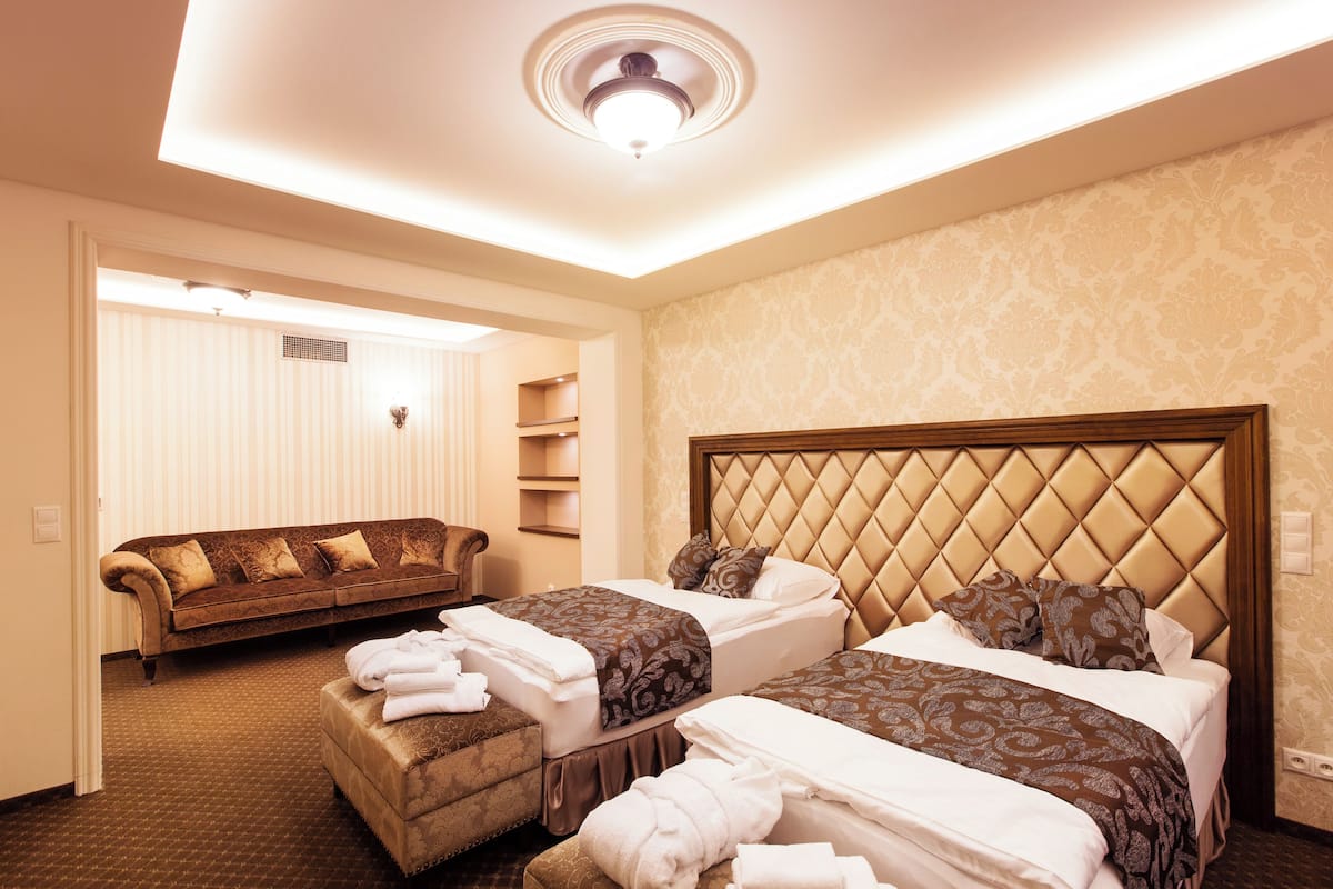 Quarto de hotel com duas camas, um sofá e um espaço para sentar.
