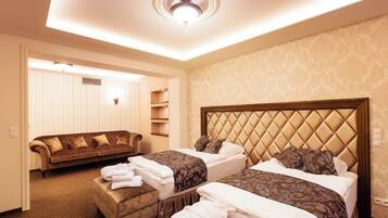 A hotel room with two beds, a sofa, and a seating area.