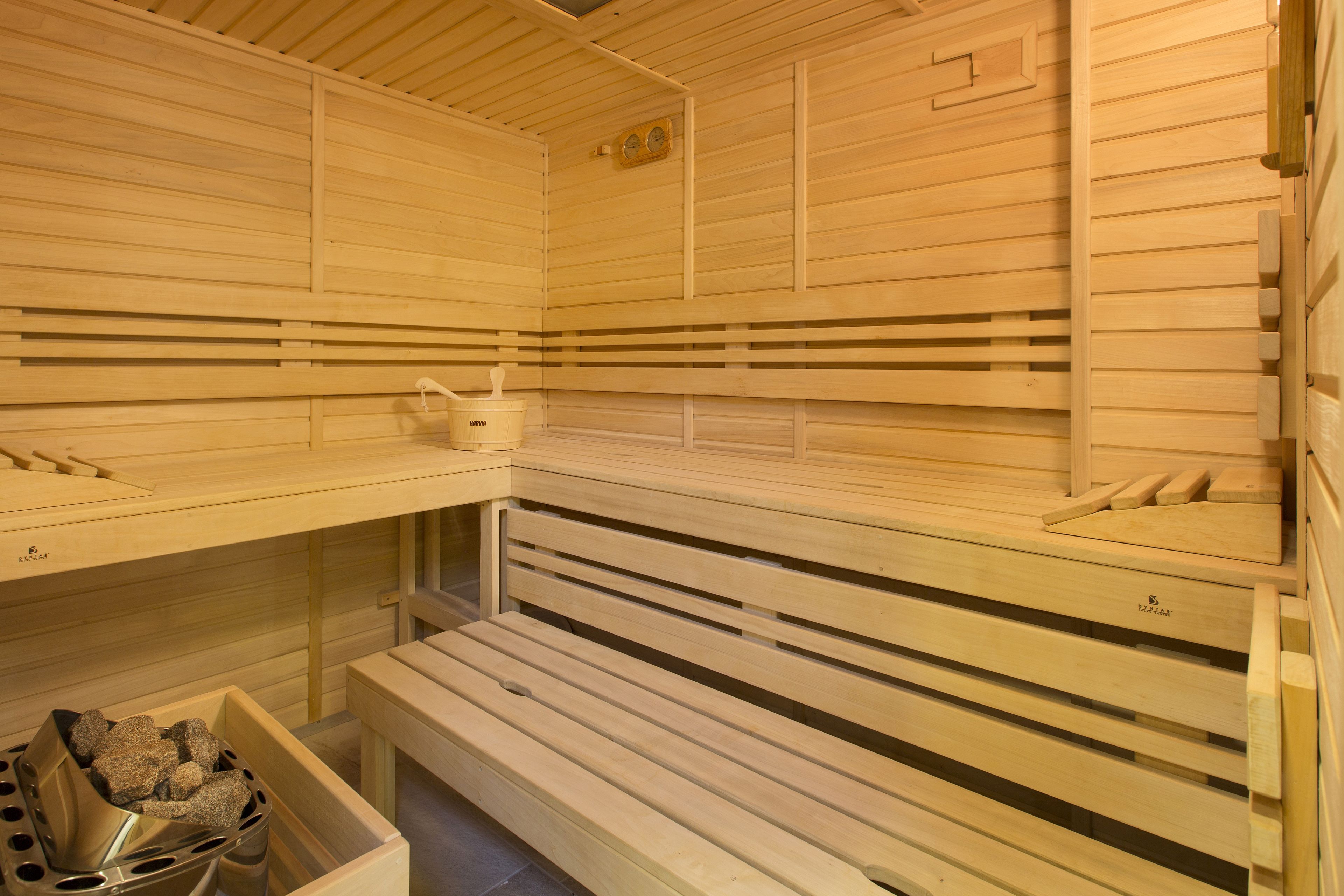 A sauna with wooden benches and a bucket of rocks.
