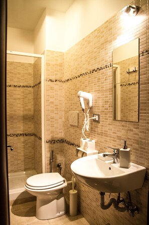 A bathroom with a toilet, sink, and hairdryer mounted on the wall. - Hotel Mosaic Central Rome (Rome)