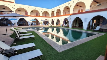 Una piscina al aire libre, sillones reclinables de piscina