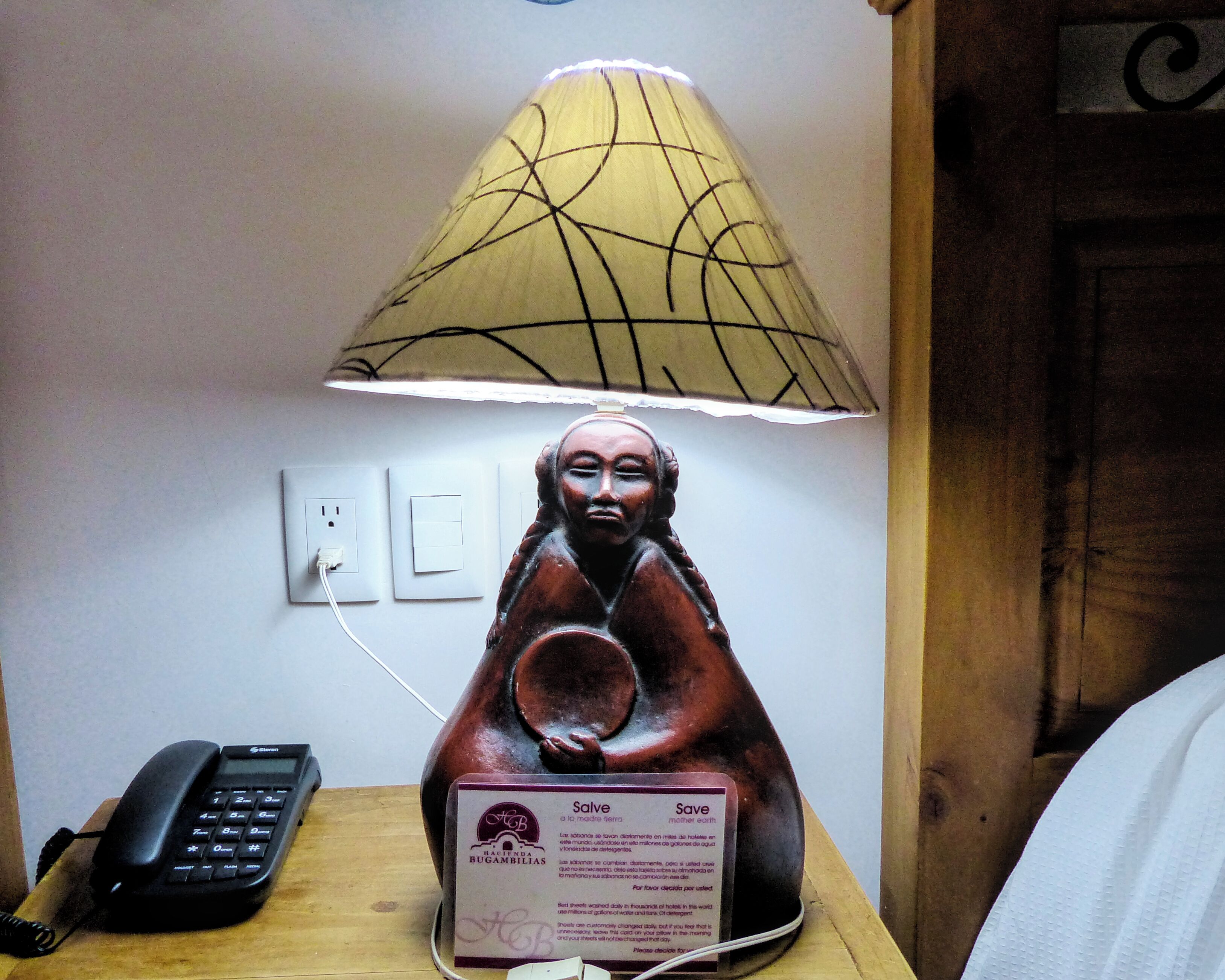 A statue of a figure with a lamp above it, a phone, and a sign with text.