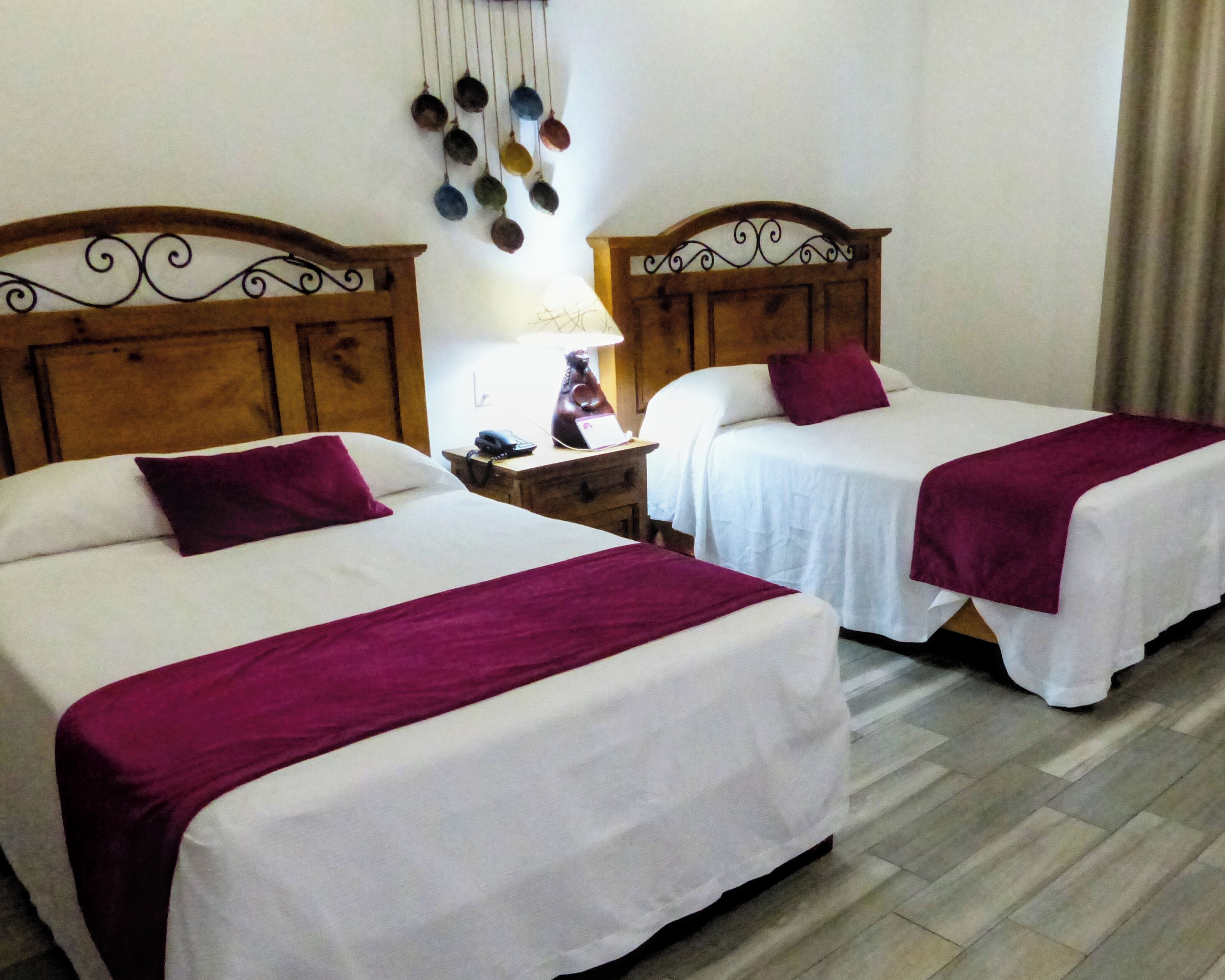 Dos camas individuales con cabeceros de madera, ropa de cama blanca y almohadones morados.
