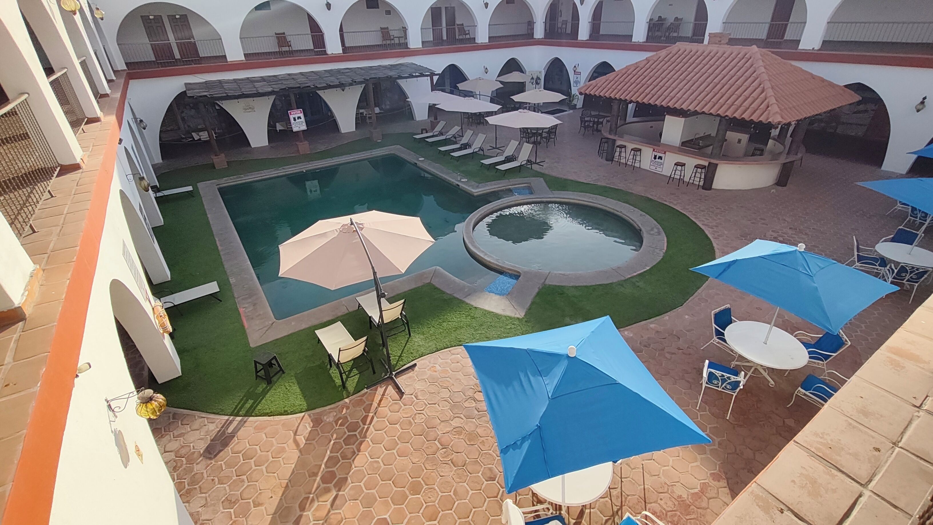 A courtyard with a swimming pool, sun loungers, and umbrellas.