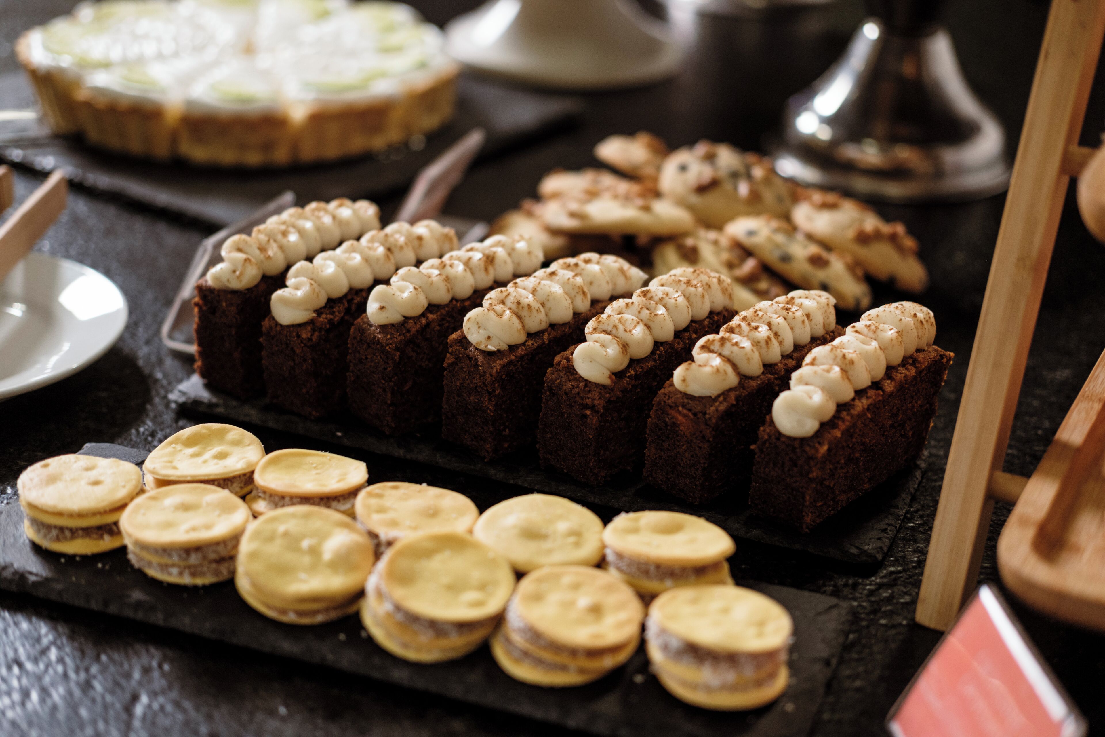 A variety of desserts on a slate board, including brownies and cookies.