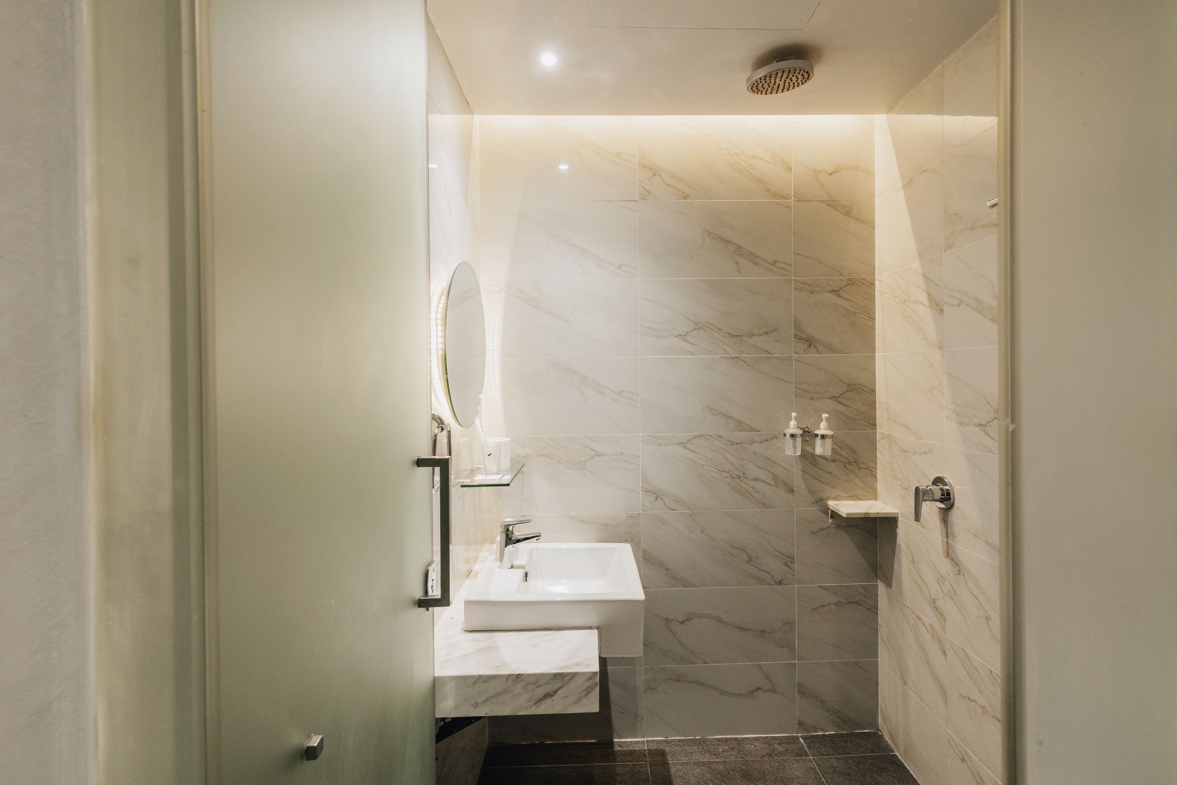 A modern bathroom with a shower, a sink, and a mirror.