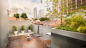 A rooftop terrace with outdoor seating, potted plants, and a view of city buildings. - Hotel Nuve (Singapore)