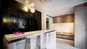 A modern kitchen with a marble countertop, dark wooden cabinets, and a built-in bench with integrated lighting. - Hotel Nuve (Singapore)