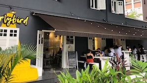 A restaurant with outdoor seating and a yellow awning. - Hotel Nuve (Singapore)