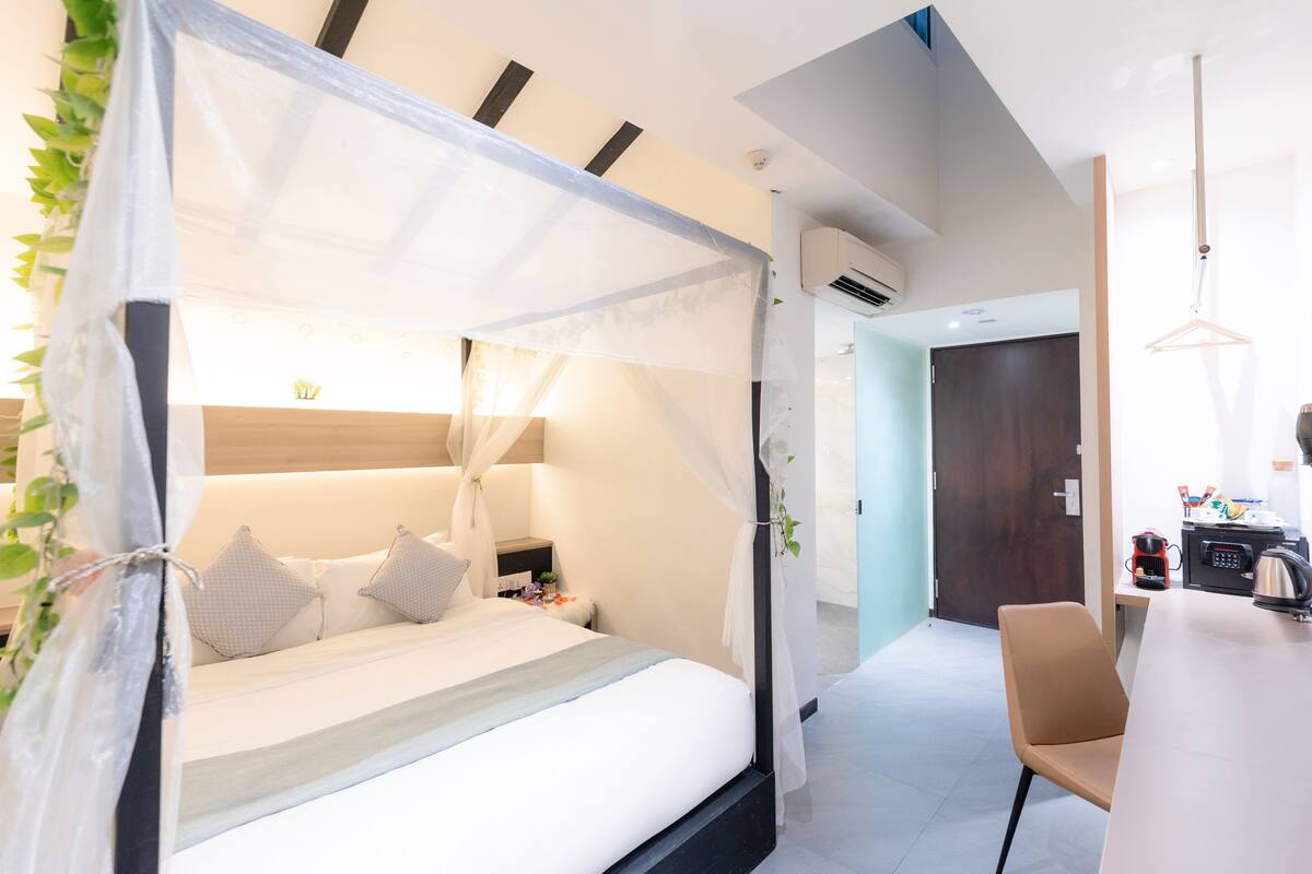 A modern bedroom with a canopy bed, bedside table, and a chair.