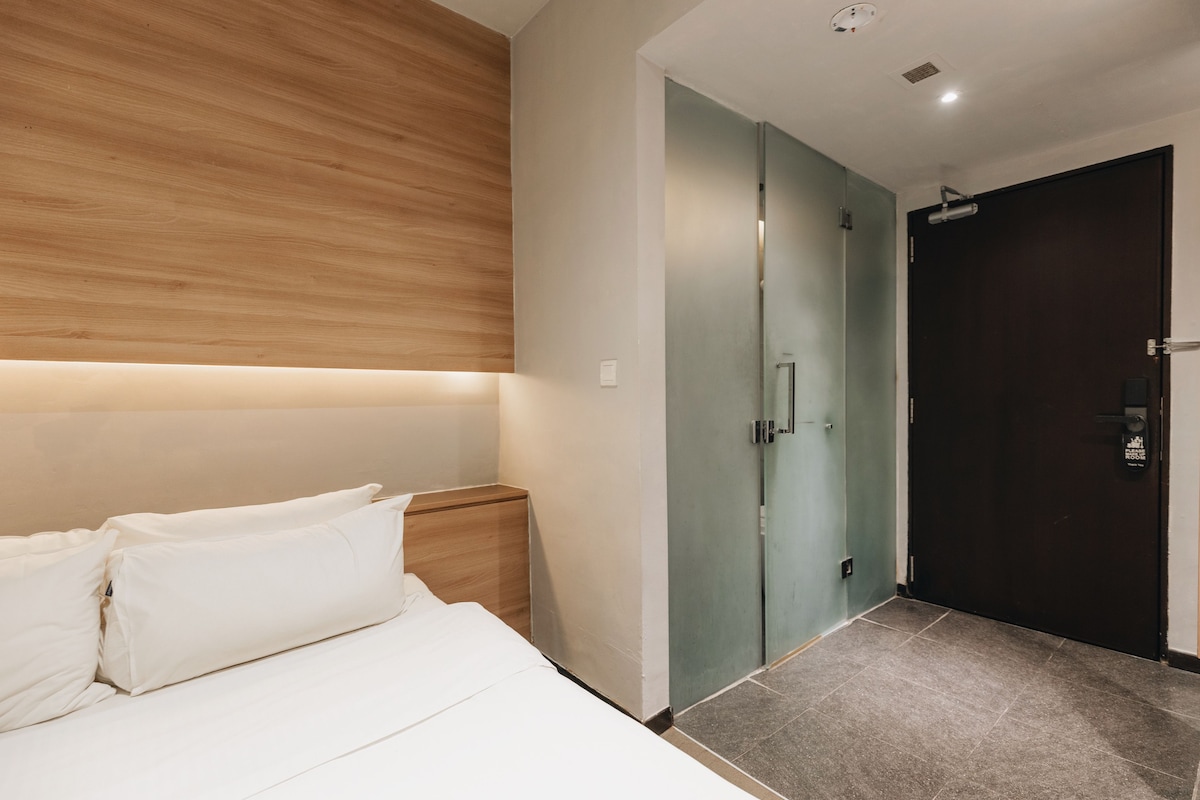 Una habitación de hotel con una cama, una mesita de noche, un armario y una puerta.