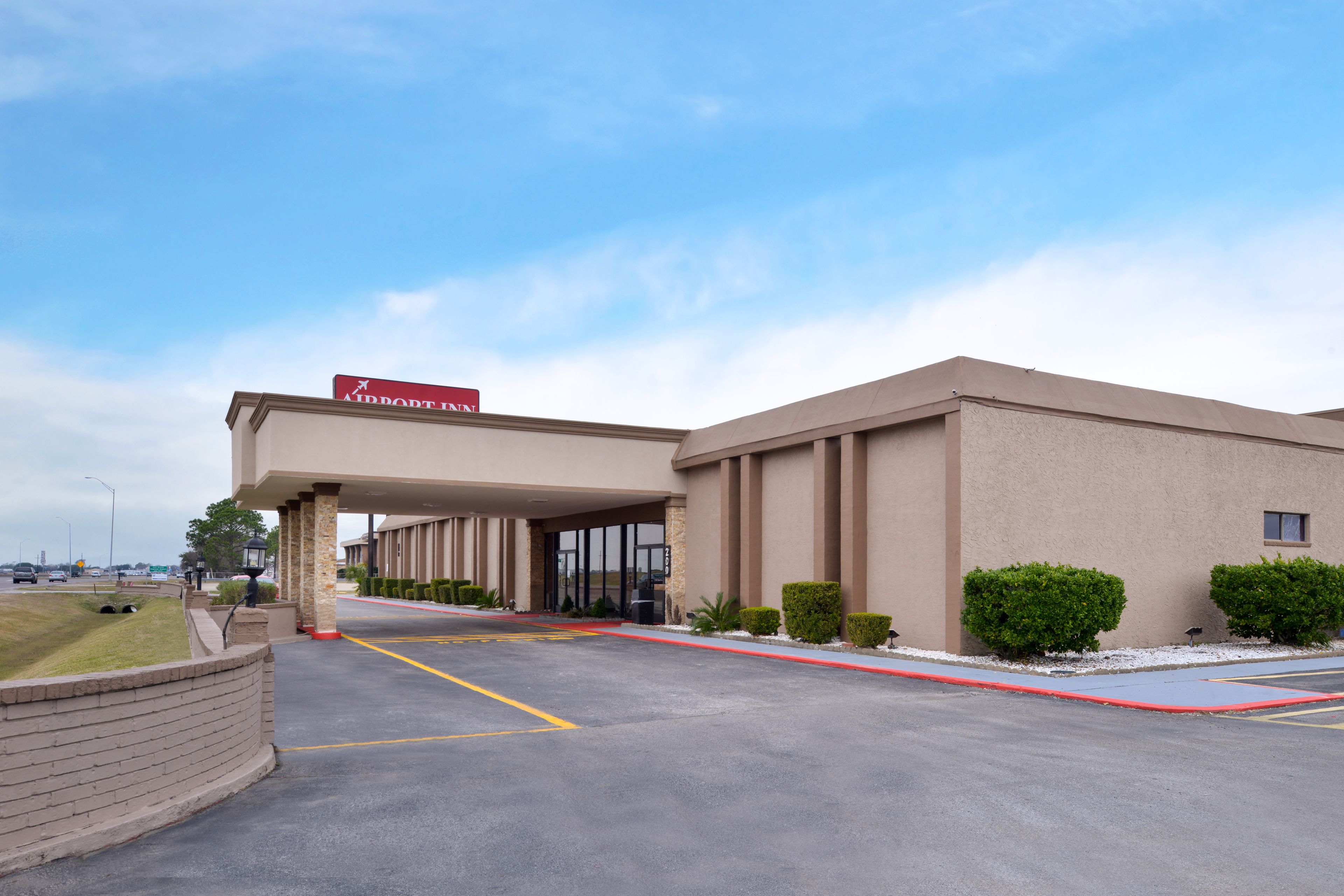 A hotel entrance with a covered driveway, a sign reading "ABROAD INN", and a parking lot with marked spaces.