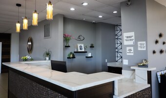 Una moderna zona de recepción con mostrador de mármol, iluminación colgante y decoración en la pared.