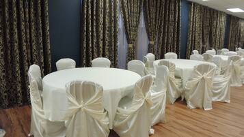 A banquet hall with round tables covered in white tablecloths and chairs with white sashes.