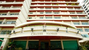 The exterior of Chaidee Mansion hotel with a curved entrance, multiple balconies, and a green awning. - Chaidee Mansion (Bangkok)
